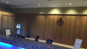 A reception desk with a granite top, blue underlighting, and a sign on the wall. - Hill Park Hotel (Dunfermline)