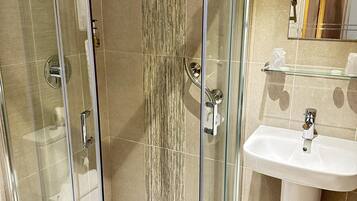 A modern bathroom with a glass-enclosed shower, a white sink, and a mirror above the sink.