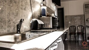 A kitchen with a stainless steel sink, a coffee machine, and two chairs. - Nine Senses Guest House (Ovar)