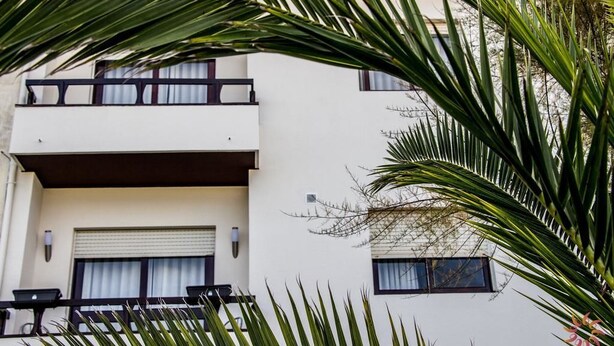 A two-story building with a balcony on the upper floor and a garage door on the lower floor. - Nine Senses Guest House (Ovar)