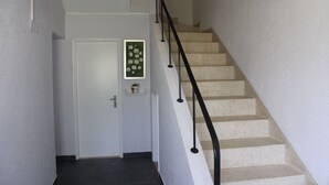 A staircase with a black handrail leading to a door with a green floral decoration. - Nine Senses Guest House (Ovar)