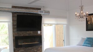 Ein Schlafzimmer mit einem großen Bett, einem Kamin aus Stein, einem Fernseher und einer Kristallleuchter.