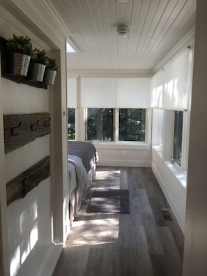 A narrow hallway with a bed, a window, and a ceiling fan. - Watermark Waterfront Cottages (Leeds and the Thousand Islands)