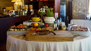 Una mesa de buffet con diversos alimentos, una tabla de madera y un florero con flores.