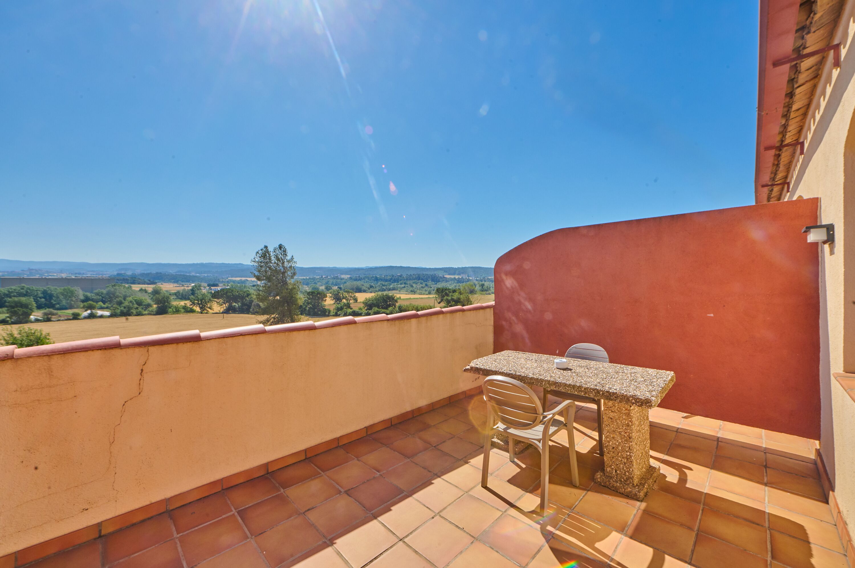 Un balcón con mesa y sillas, con vista a un paisaje pintoresco.