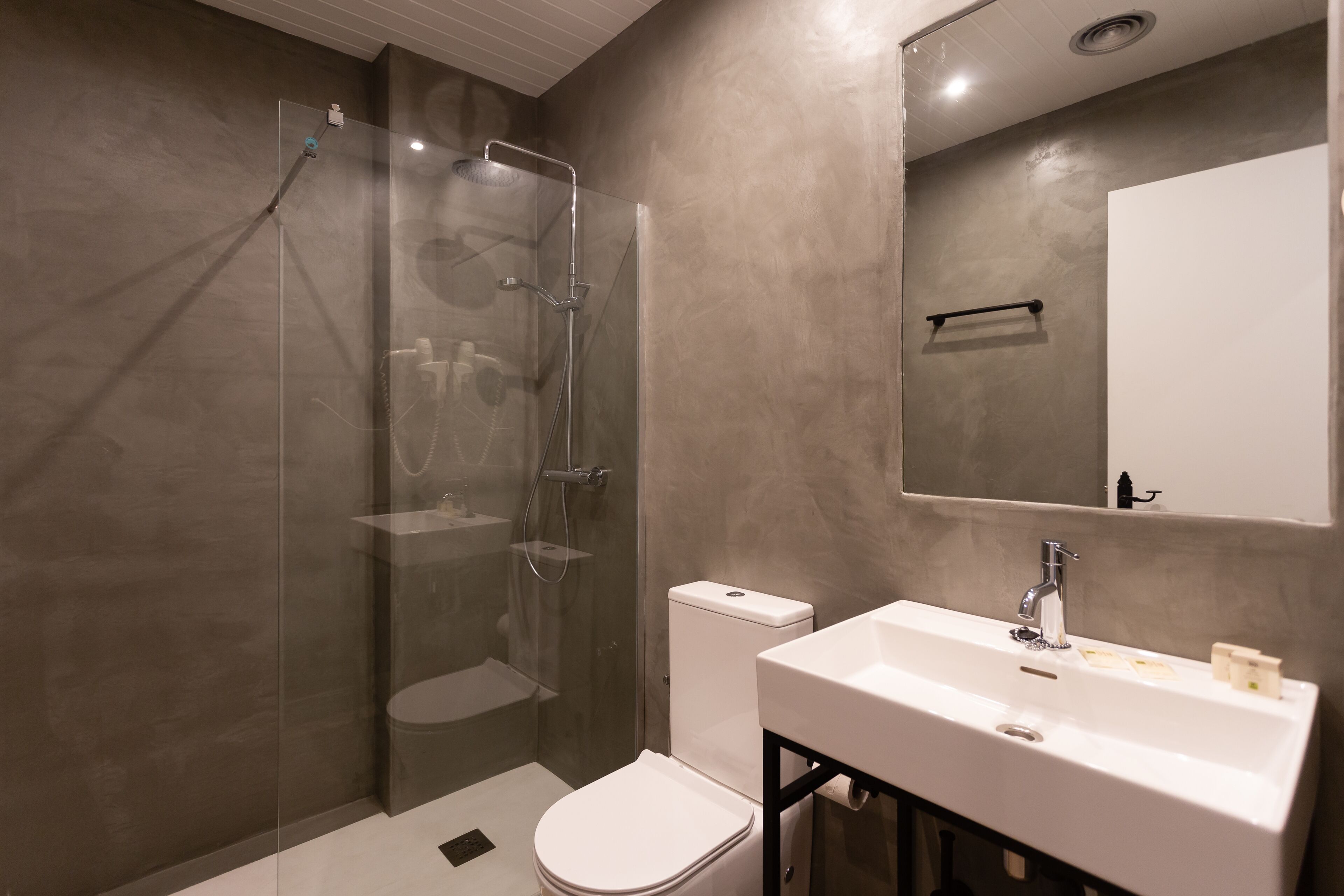 A modern bathroom with a glass-enclosed shower, a white toilet, and a sink with a mirror above.
