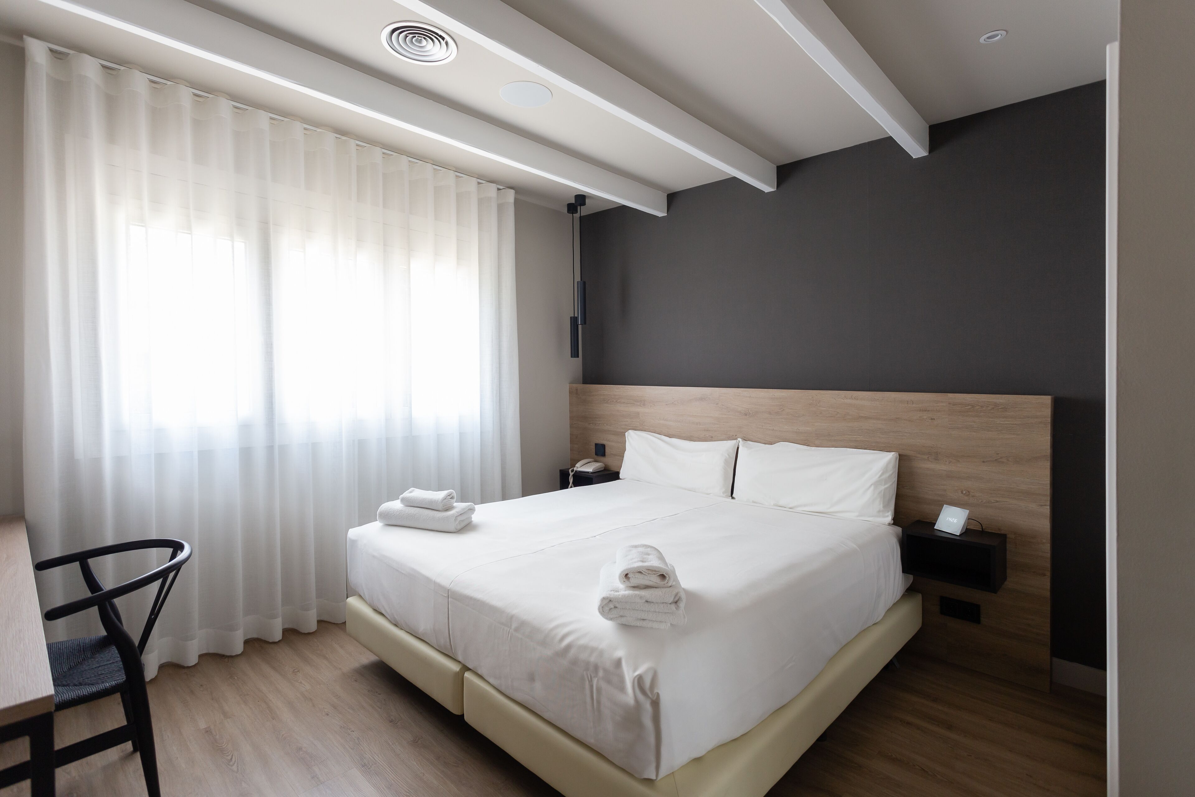 Una habitación de hotel moderna con una cama grande, un escritorio y una silla.
