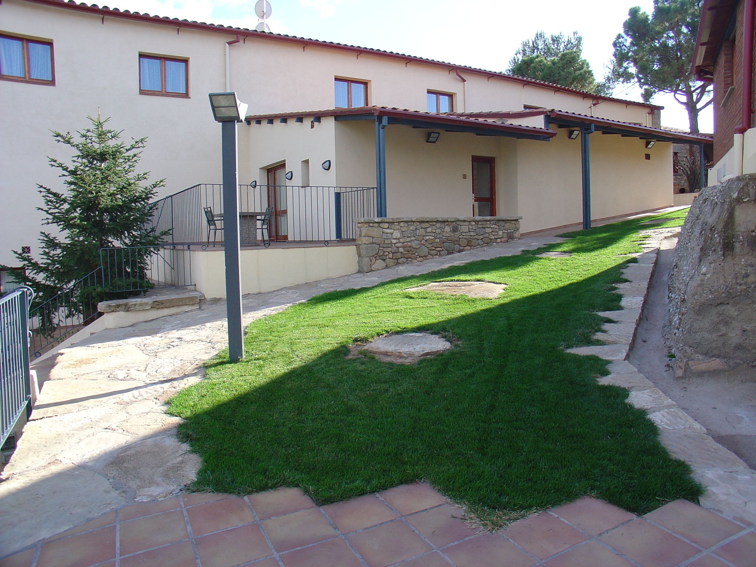 A building with a stone facade, a tiled patio, and a well-maintained lawn.