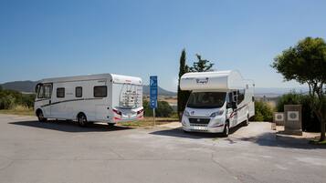 Dos vehículos recreativos estacionados en un camping con vista despejada al paisaje circundante.