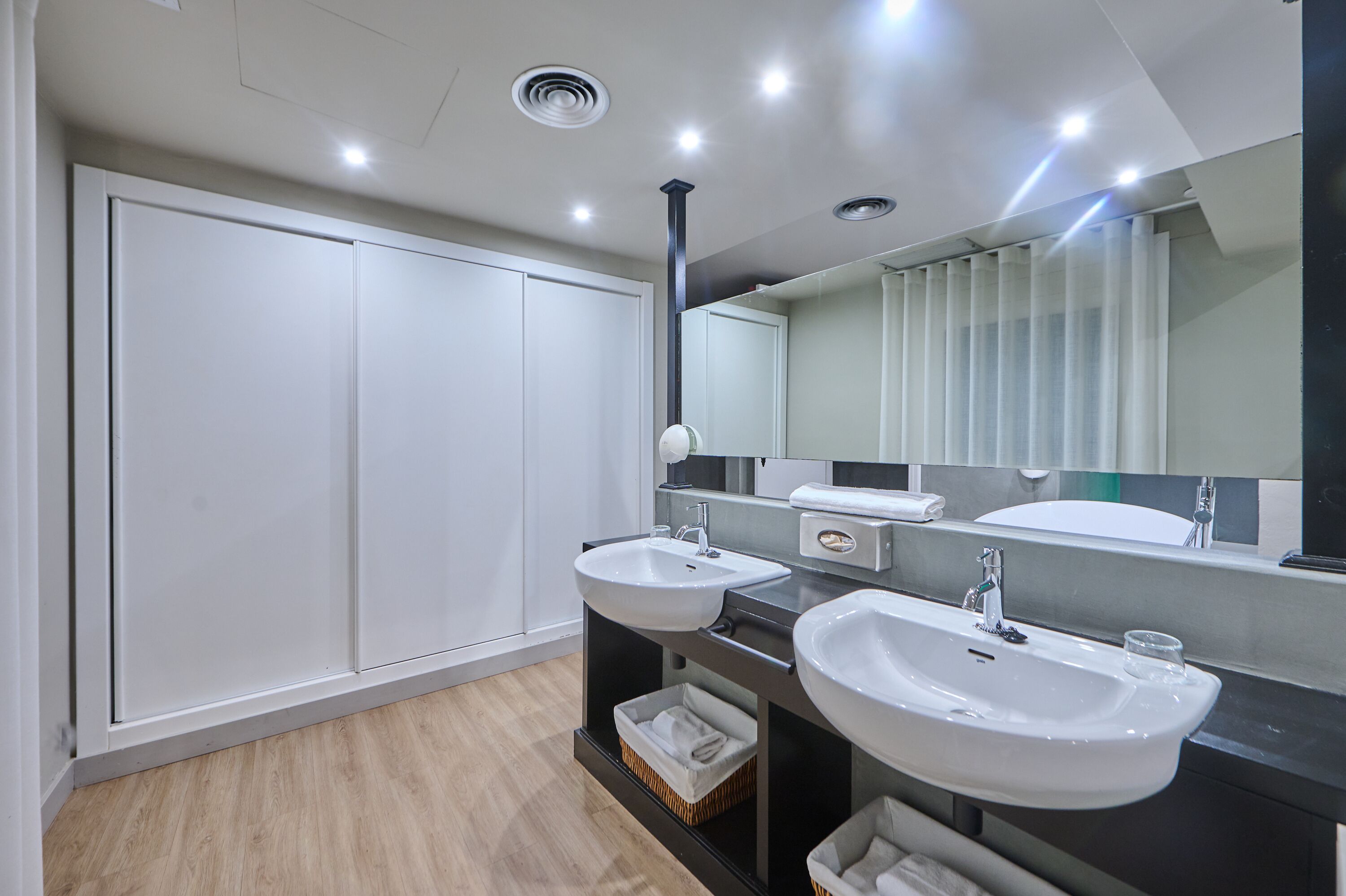 Une salle de bain moderne avec deux lavabos, un grand miroir et une armoire.