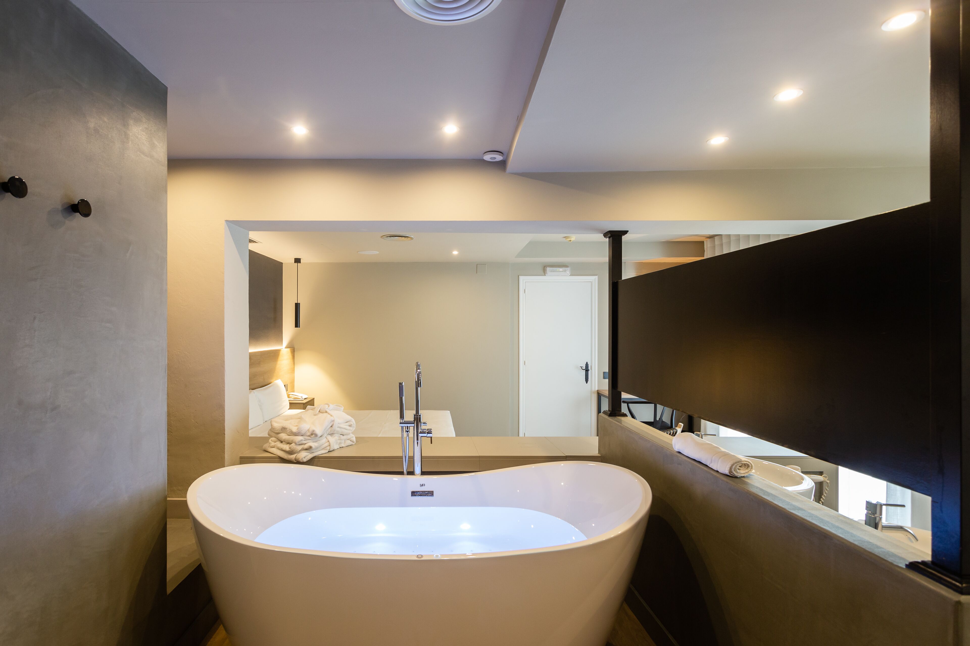 A modern bathroom with a freestanding bathtub, a large mirror, and recessed ceiling lighting.