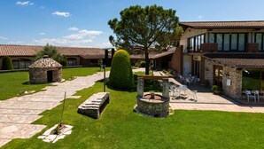 Un patio con senderos de piedra, una fuente de piedra y un césped bien cuidado.