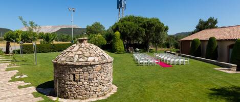 Una estructura de piedra en un jardín bien cuidado con cielo despejado.