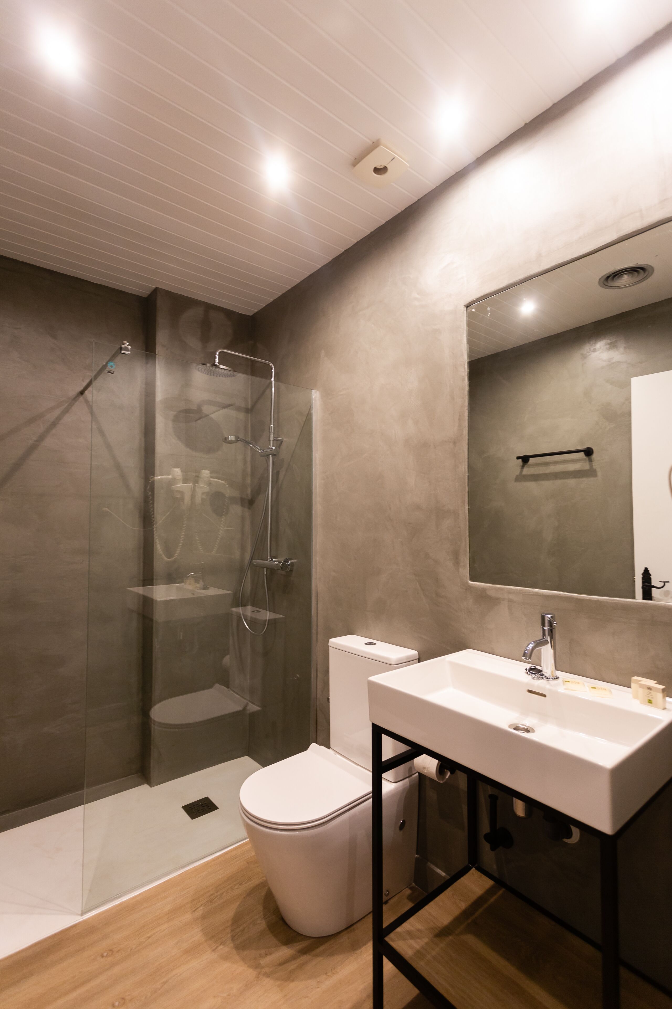 A modern bathroom with a glass-enclosed shower, a white toilet, and a vanity with a mirror.