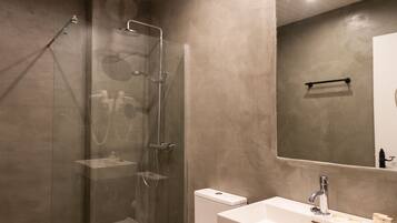 A modern bathroom with a glass-enclosed shower, a white toilet, and a vanity with a mirror.