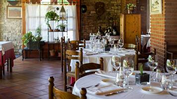 Un restaurante con varias mesas redondas preparadas para comer, con manteles blancos y copas de vino.