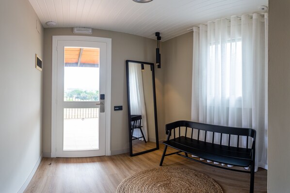A room with a wooden floor, a black bench, a mirror, and a door leading to an outdoor balcony. - Hotel Mas de la Sala (Sallent)