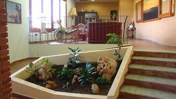 A reception area with a staircase, a small garden with plants and rocks, and a seating area with chairs and a table.