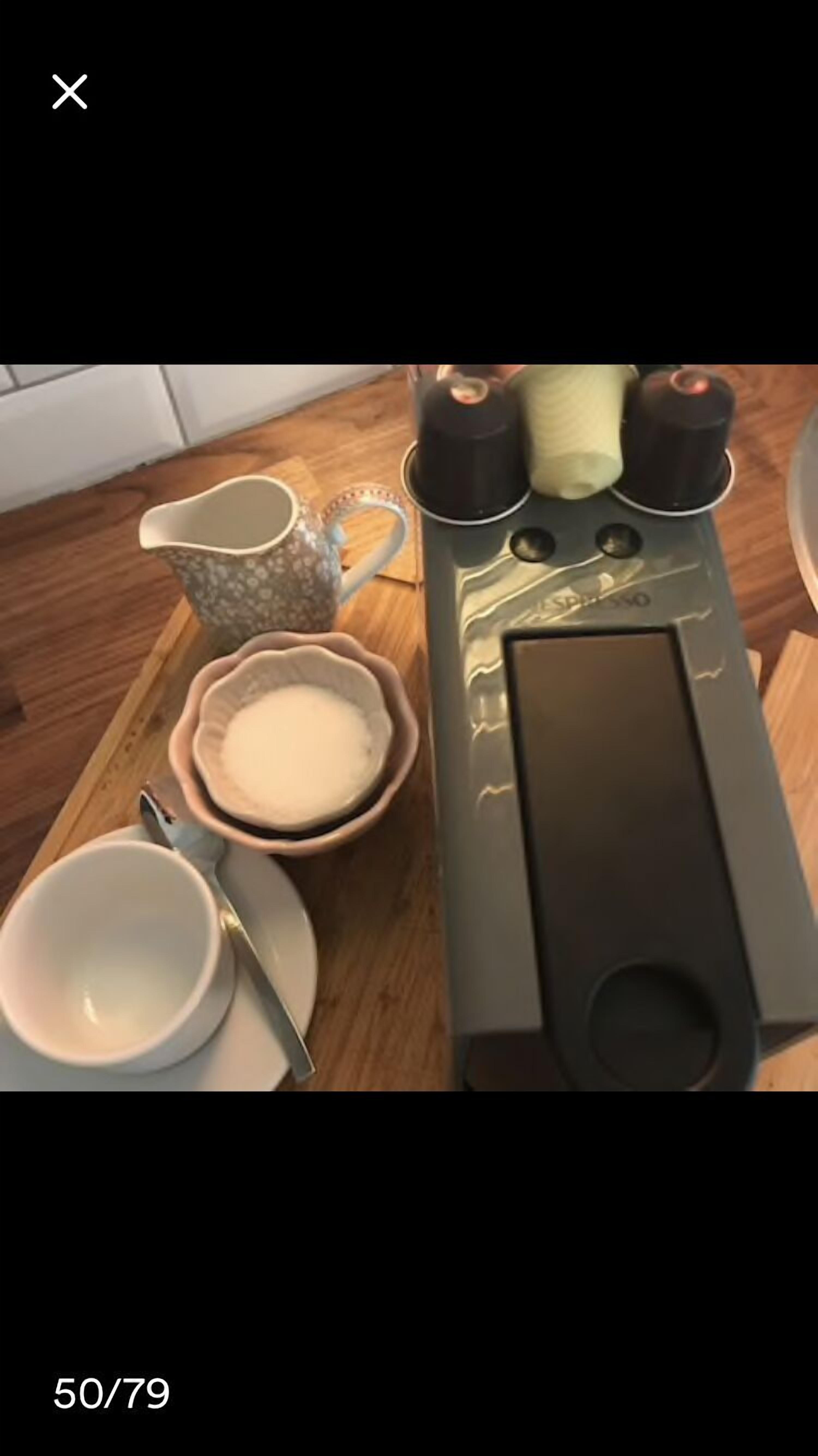 A kitchen counter with a coffee maker, a bowl of sugar, a cup, and a mug.