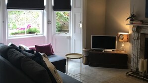 Una sala de estar con un sofá, televisión, chimenea y una ventana con persianas.