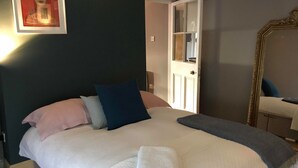 Una cama bien hecha con almohadas y una toalla doblada, una obra de arte enmarcada en la pared y un espejo.