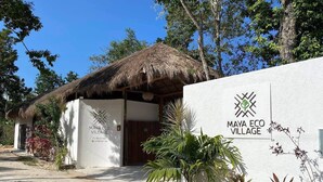 A thatched-roof building with a sign for Maya Eco Village, surrounded by greenery. - Maya Eco Village (Akumal)