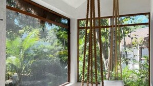 A room with a large window, a hanging swing, and a bed. - Maya Eco Village (Akumal)