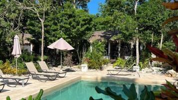 Alberca al aire libre, sombrillas en la alberca y camastros