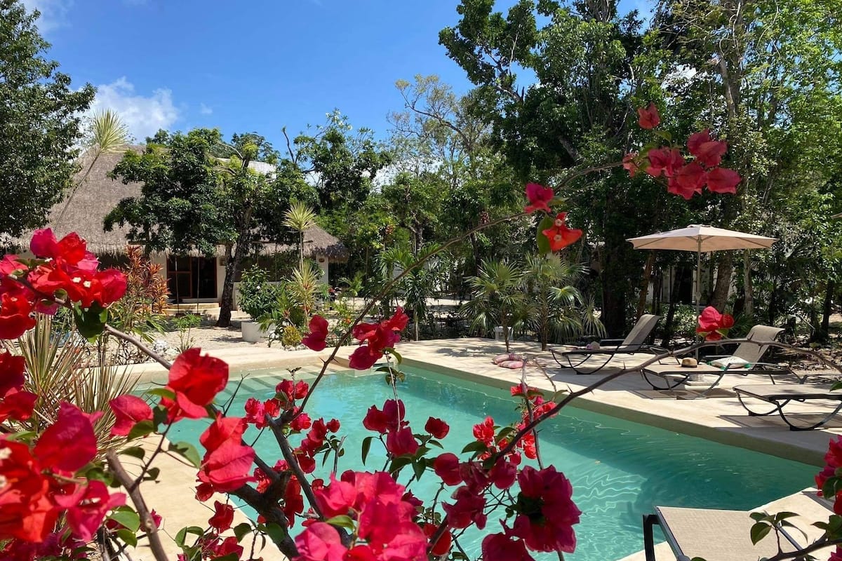 A pool area with lounge chairs and a thatched-roof structure.