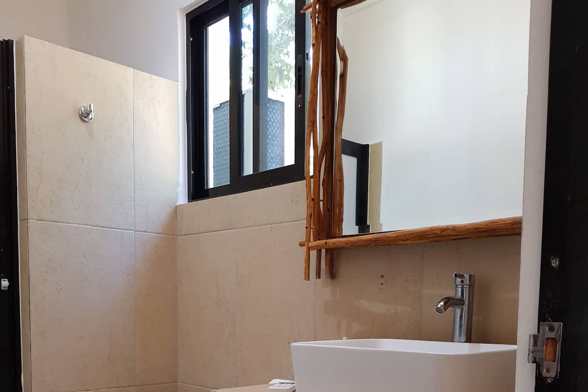 A modern bathroom with a white toilet, a beige sink, and a mirror above it.