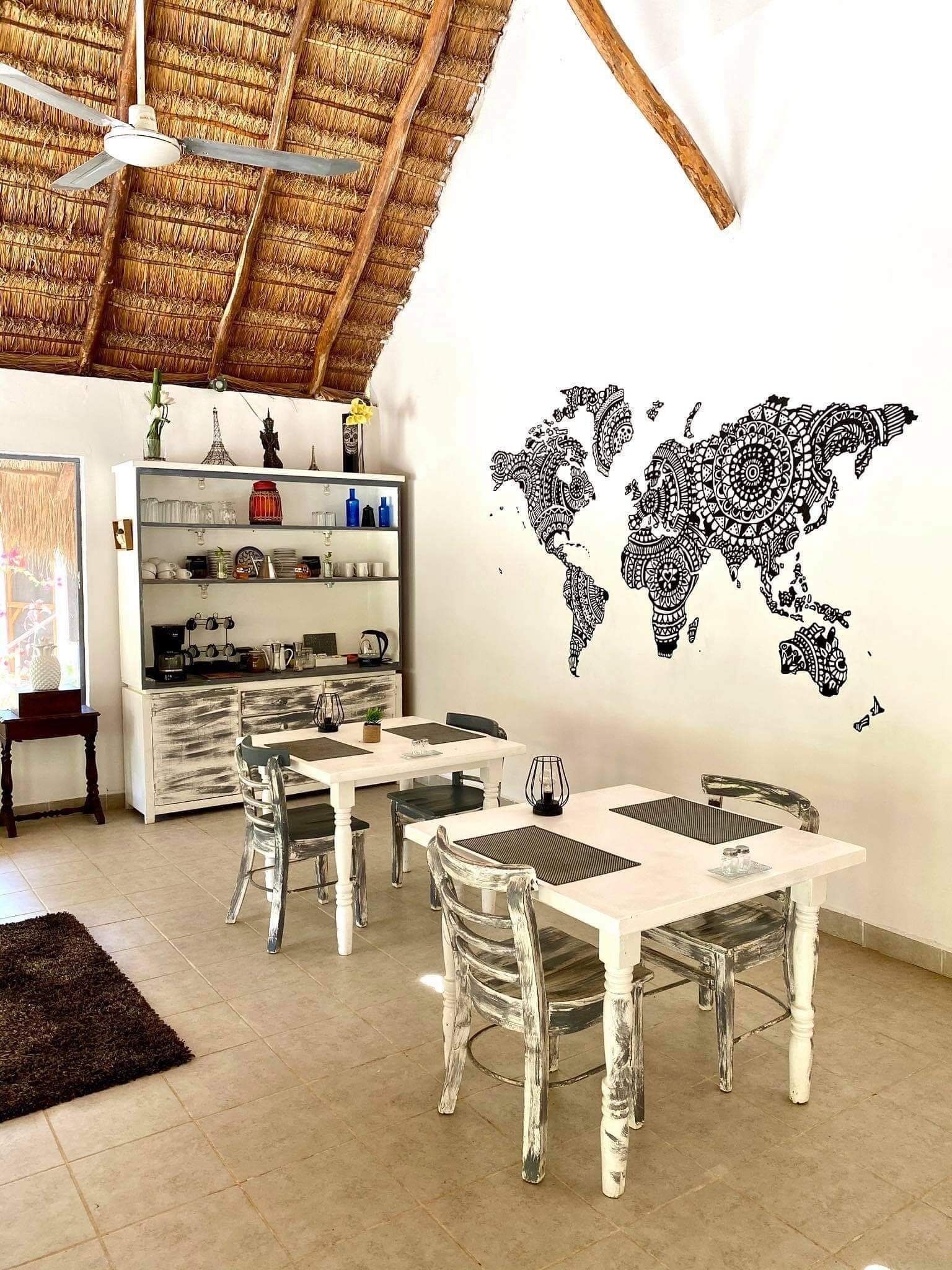 A dining area with a white table and chairs, a ceiling fan, and a world map mural on the wall.