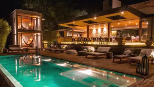 Un área de piscina moderna al aire libre con sillones de descanso y un bar.