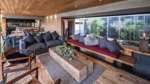 Una sala de estar moderna con techo de madera, un sofá, una mesa de centro y vistas al exterior.