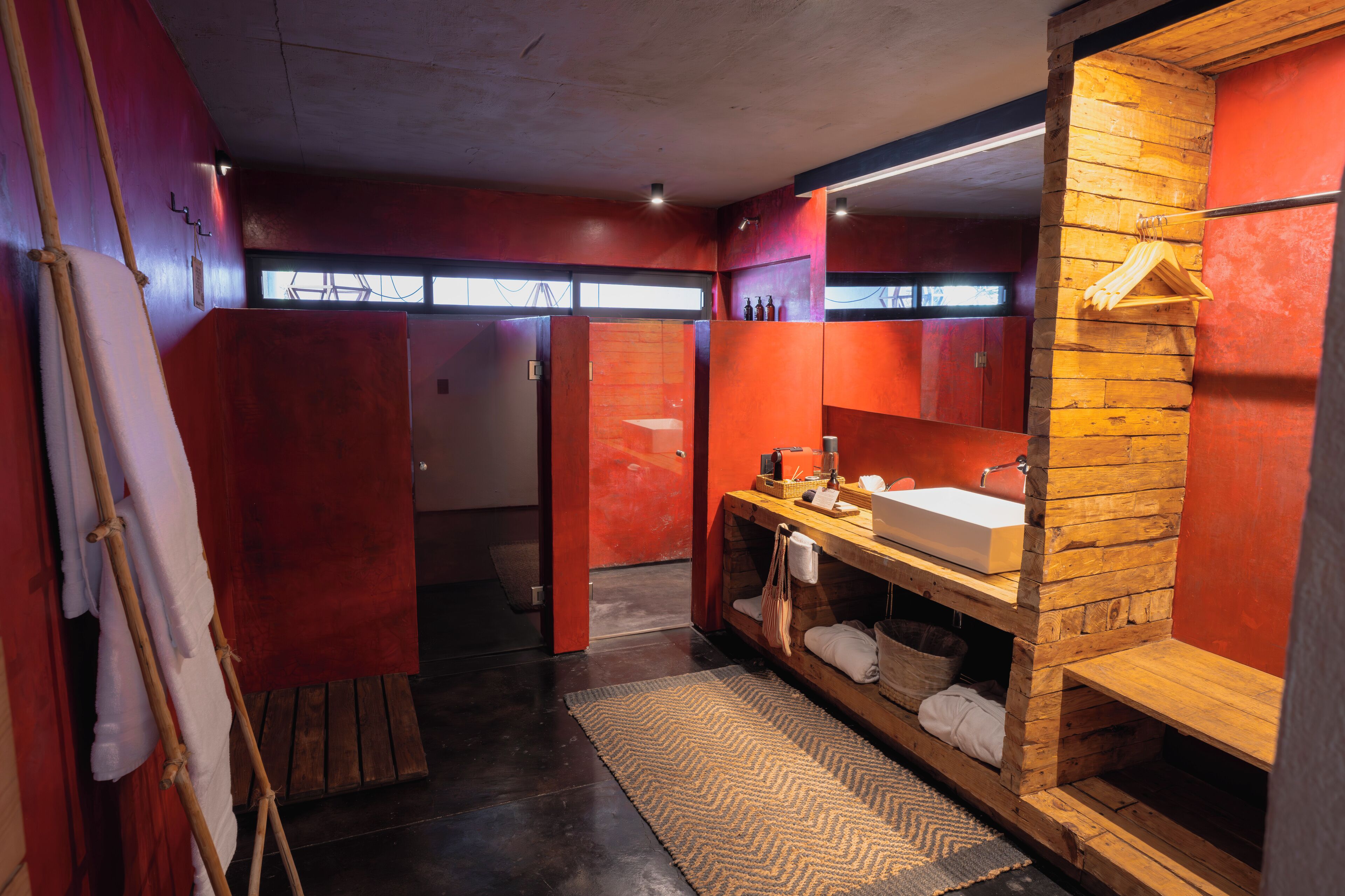 Un baño moderno con tocador de madera, un espejo grande y un perchero para toallas.