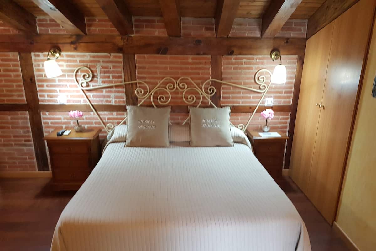 A bedroom with a wooden headboard, a brick wall, and a wooden wardrobe.