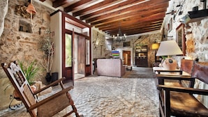 A rustic interior with stone walls, wooden beams, a stone floor, and traditional furnishings. - Can Guillo (Pollenca)