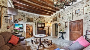 A rustic living room with a checkered floor, wooden furniture, and stone walls. - Can Guillo (Pollenca)