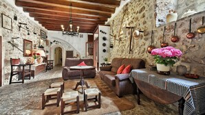 A rustic interior with stone walls, wooden beams, and traditional furnishings. - Can Guillo (Pollenca)