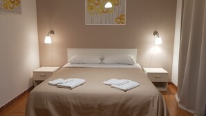 A neatly made bed with two folded towels, a white headboard, and two bedside lamps. - B&B Mimosa (Giardini Naxos)