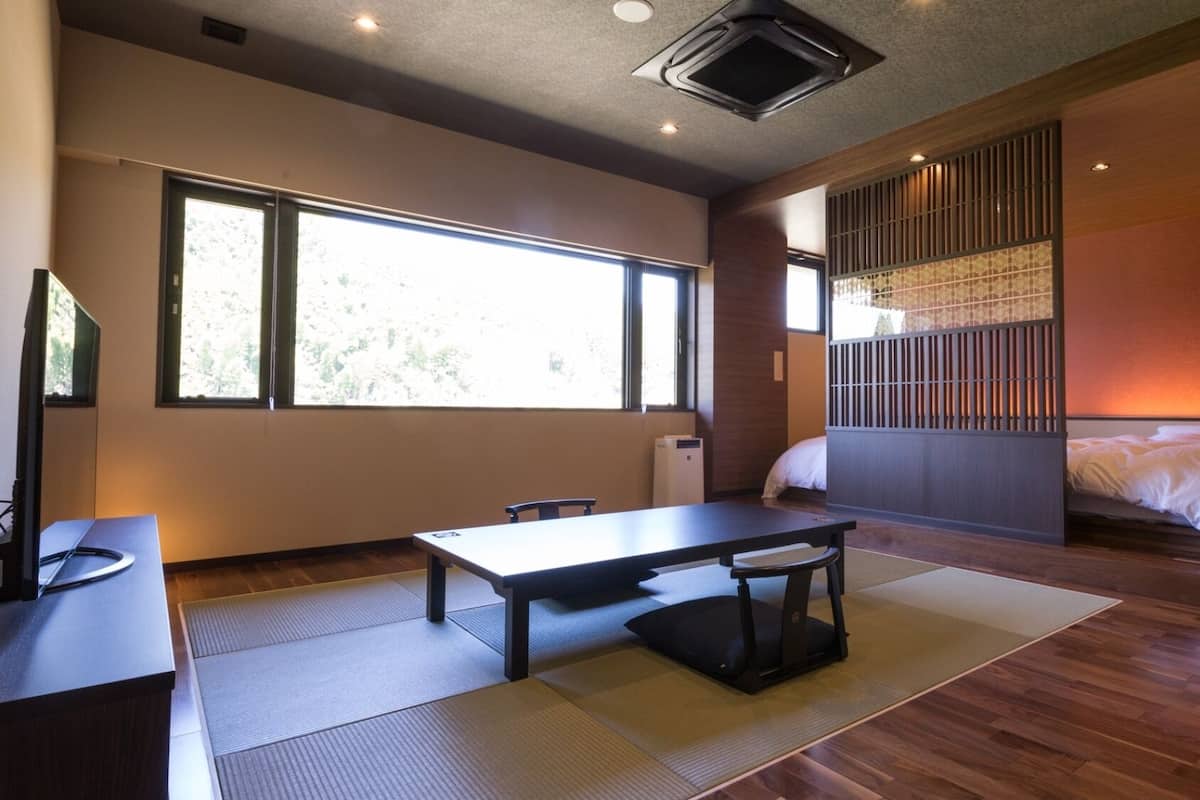 A room with a bed, a desk, and a large window.