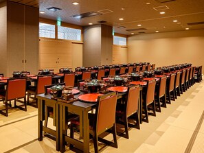 Un amplio salón de conferencias con filas de mesas y sillas, equipado con lámparas de mesa e iluminación empotrada en el techo.