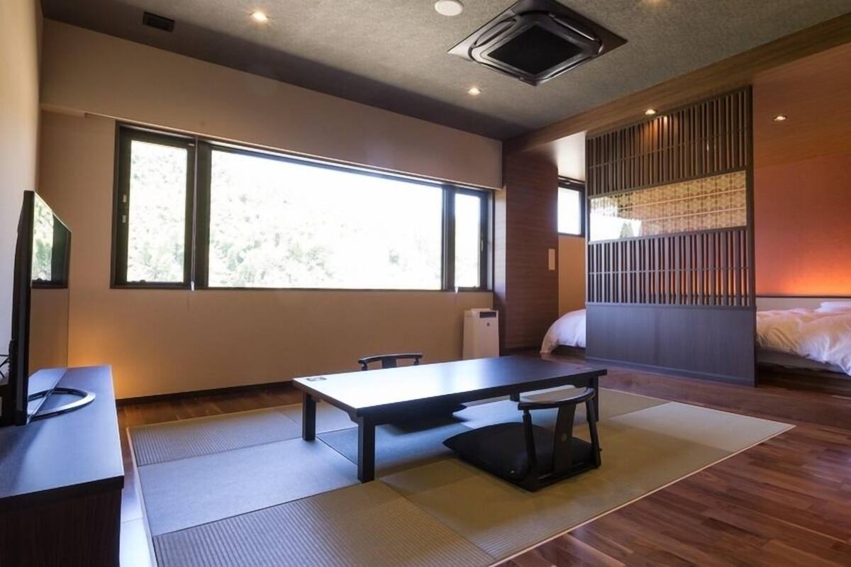 Una habitación con cama, escritorio, silla, ventana y puerta corredera.