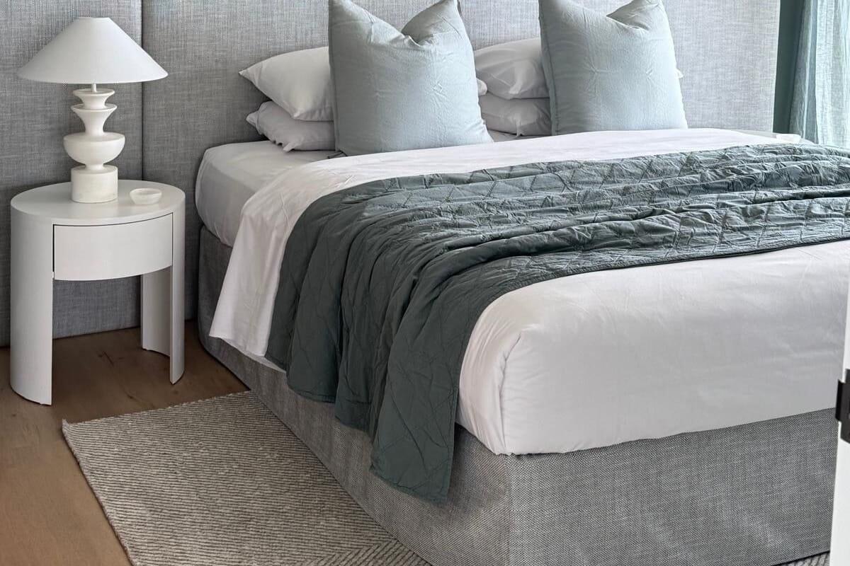 Ein Schlafzimmer mit Bett, Nachttisch, Lampe und Deckenventilator.