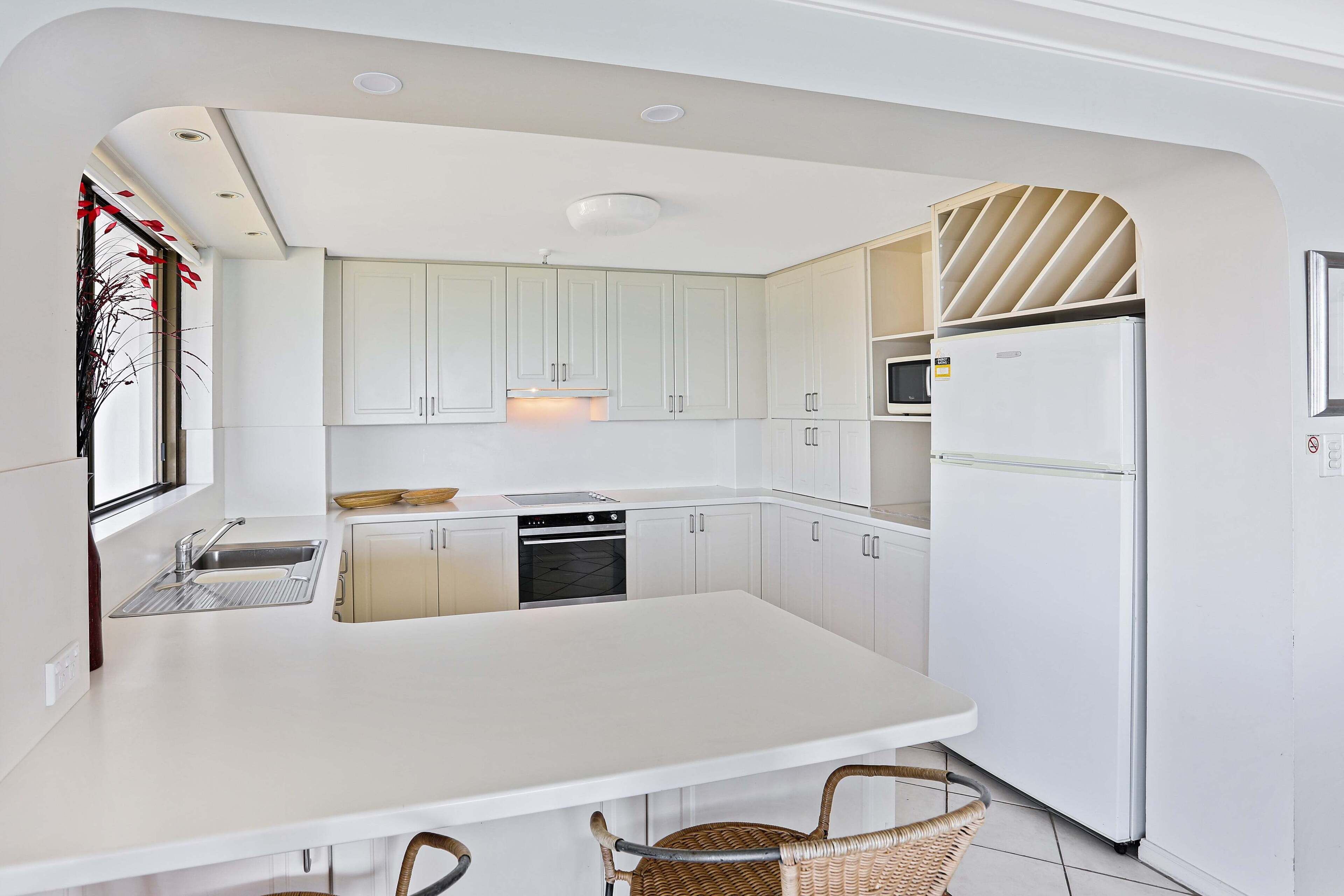 A modern kitchen with white cabinetry, a central island, and a built-in microwave.