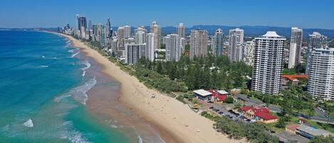 Un paisaje urbano costero con playa, rascacielos y cielo azul despejado.