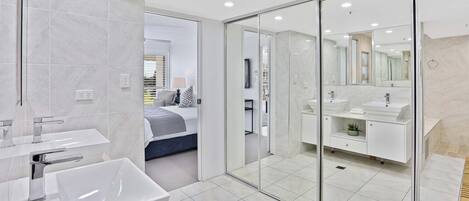 A modern bathroom with a large mirror, two sinks, and a bathtub.