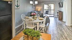 A dining area with a wooden table, white chairs, and a vase of flowers. - Hilton Head Condo w/ Pool Bar: Walk to Beach! (Hilton Head Island)