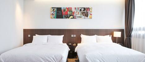 Habitación de hotel con dos camas, un reposapiés rojo, una obra de arte abstracta grande en la pared y una ventana con cortinas.