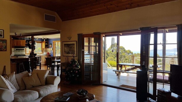 A cozy living room with a sofa, coffee table, and a view of the outdoors through large windows. - Fantastic getaway for family or friends with spectacular views. (Snug)