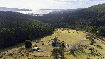 An aerial view of a rural property with a large field, a house, and a small building.